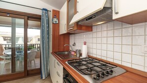 Una cocina con estufa a gas, lavamanos y puerta corrediza de vidrio que da a un área de estar al aire libre.
