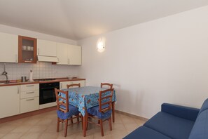 Une cuisine compacte comprenant une table à manger, des chaises, un canapé et un luminaire fixé au mur.