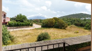 Paisaje rural con un edificio rosa, una carretera pavimentada y una colina al fondo.