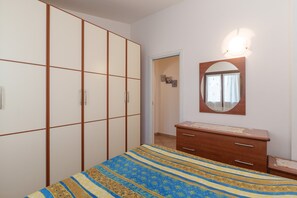Une chambre à coucher comprenant un lit, une armoire, une commode et un miroir.