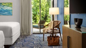 A hotel room with a bed, a chair, a desk, a lamp, and a view of greenery outside. - 1BR 2 Queen | Saddlebrook Resort | Poolside Dining, Spa & Golf | 2 Units (Wesley Chapel)