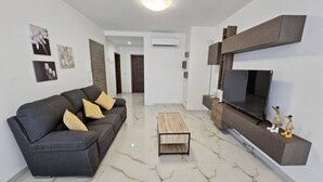 Una sala de estar moderna con sofá, mesa de centro, televisor y estanterías en la pared.