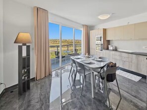 A modern hotel room with a balcony, a dining area, and a kitchen. - 5th Floor enjoying open views of the National  Park, 2 bedroom 2 Bathroom (San Pawl il-Baħar)