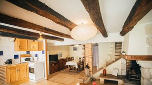 Eine rustikale Küche mit Holzbalken, einem Essbereich mit Tisch und Stühlen sowie einem Kamin.