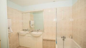 Un baño con dos lavamanos, un espejo, cabina de ducha de vidrio y un inodoro.