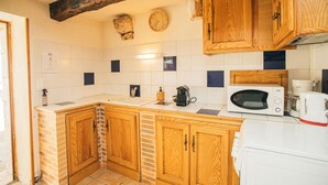 Eine Küche mit Holzausstattung, einer Mikrowelle, einer Kaffeemaschine und einer Uhr an der Wand.
