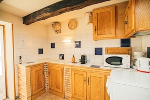 Une cuisine avec des meubles en bois, un four à micro-ondes, une machine à café et une horloge au mur.