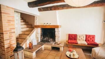 Una sala de estar acogedora con chimenea, un sofá, una mesa de centro de madera y una escalera.