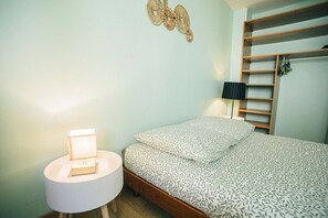 Ein Schlafzimmer mit Bett, Nachttischlampe, Wanddekoration und integriertem Regal.