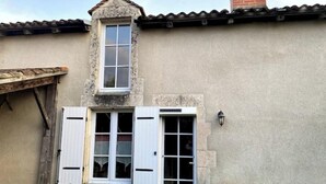 A building with a stone facade, a small window with shutters, and a door with a window.