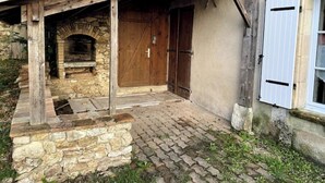 A rustic building with a stone fireplace, wooden door, and a brick-paved entrance.