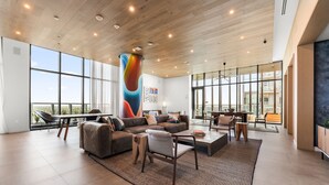A spacious living area with a large sectional sofa, a coffee table, and a modern fireplace. - Luxury Downtown Austin Condo Near Rainey Street (Austin)