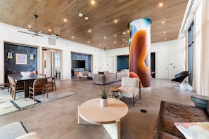 Un vestíbulo amplio con techo de madera, un pilar grande, una zona de comedor y un área de descanso.
