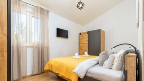 A modern bedroom with a bed, a TV, and a wooden cabinet. - Charming apartment in fabulous Pula with refreshing AC (Pula)