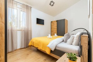 A modern bedroom with a bed, a TV, and a wooden cabinet. - Charming apartment in fabulous Pula with refreshing AC (Pula)