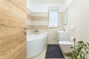 A modern bathroom with a bathtub, toilet, and sink, featuring wooden paneling and a small window. - Charming apartment in fabulous Pula with refreshing AC (Pula)