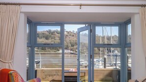 Quarto com uma grande porta de vidro deslizante que dá para uma vista da marina, uma cadeira colorida, uma pequena mesa e um sofá.