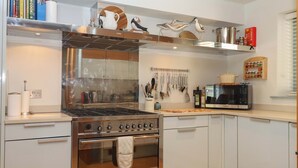 Uma cozinha moderna com forno embutido, micro-ondas e diversos utensílios pendurados na parede.