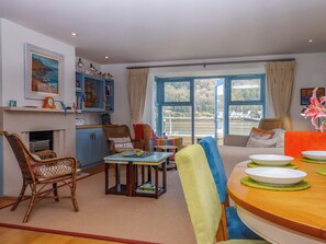 A living room with a dining area, a fireplace, a large window with a view, and a bookshelf. - 26 Dart Marina (Dartmouth)