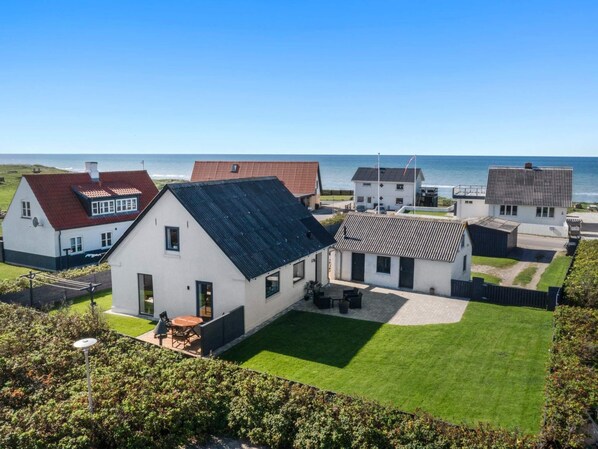 A coastal residential area with houses, a lawn, and a view of the sea. - 4 Star Holiday Home in Lokken (Lokken)