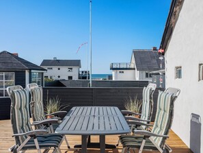 A patio with a table and chairs, a flagpole, and buildings in the background. - 4 Star Holiday Home in Lokken (Lokken)