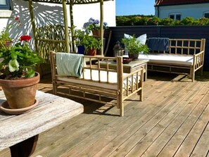 A wooden deck with a wooden bench and a small table. - 4 Star Holiday Home in Lokken (Lokken)