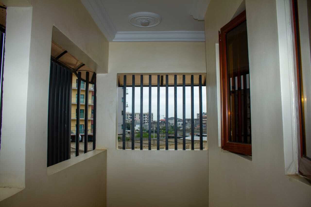 A narrow corridor with barred windows and a view of buildings outside.