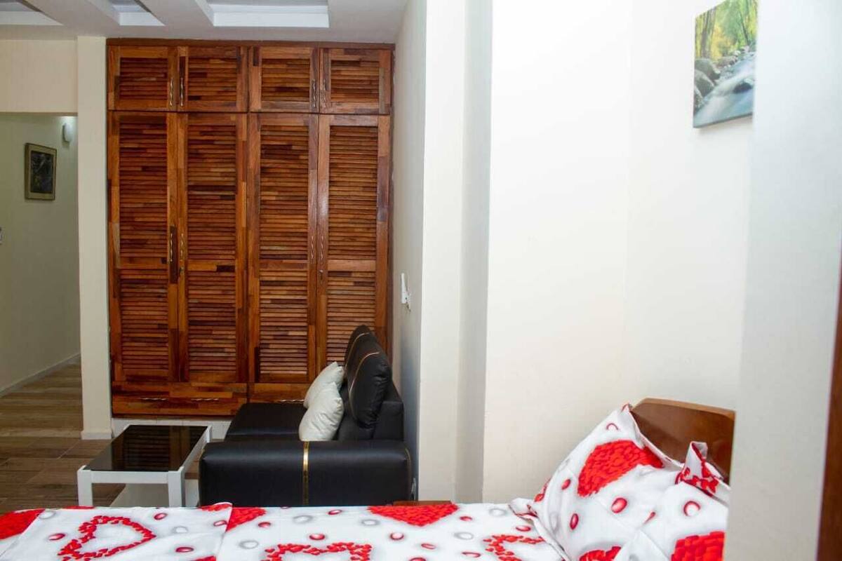Une chambre à coucher avec un lit, une armoire en bois, une petite table et un tableau accroché au mur.