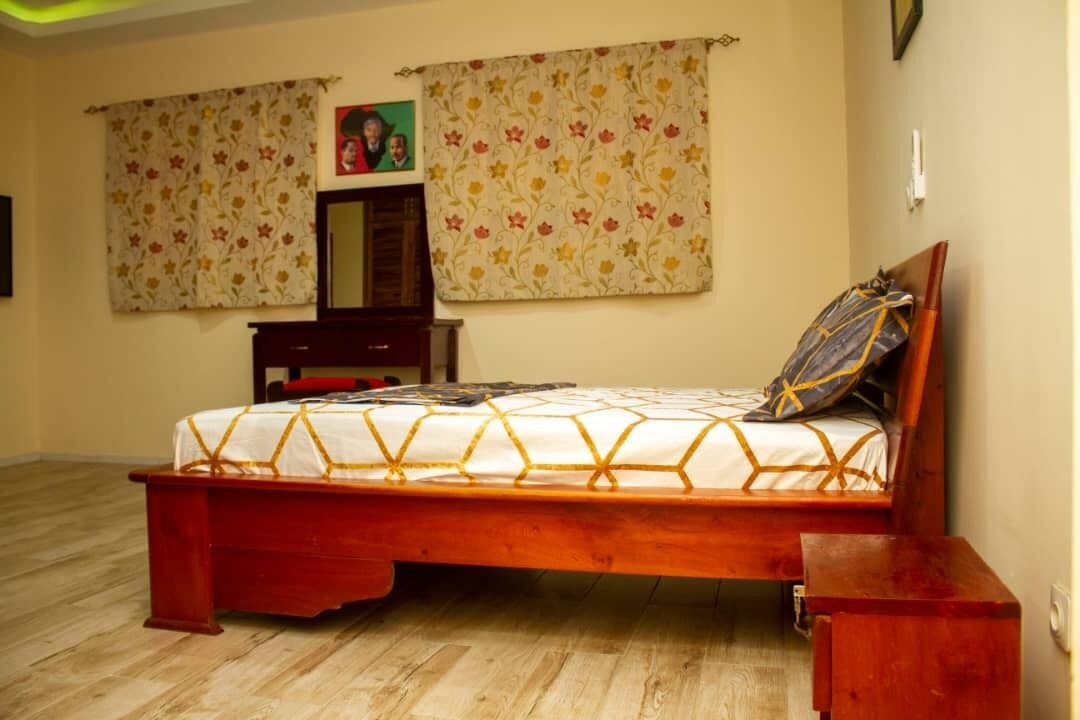 A bedroom with a wooden bed, a nightstand, a dresser, a mirror, and floral curtains.