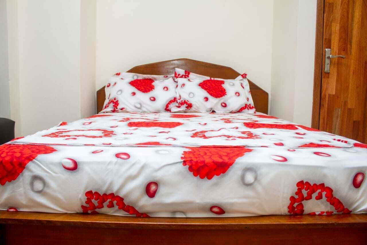Una cama con una colcha y almohadas a cuadros blancos y rojos.