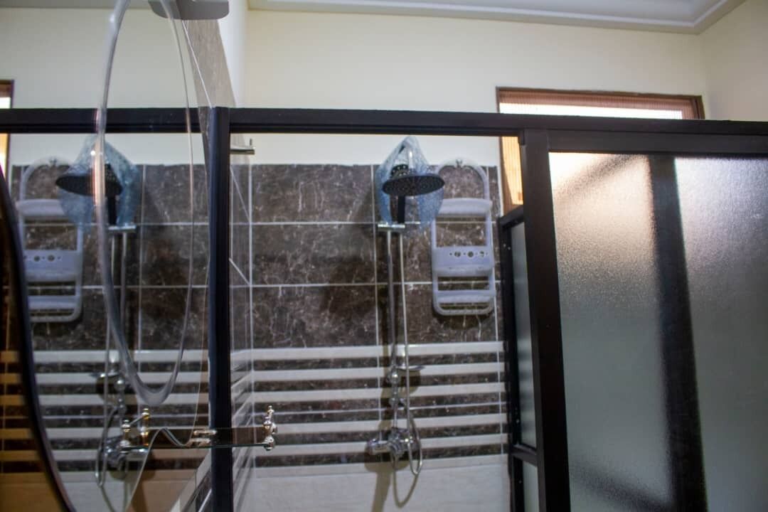 A bathroom with a glass-enclosed shower area, a tiled wall, and a visible showerhead.