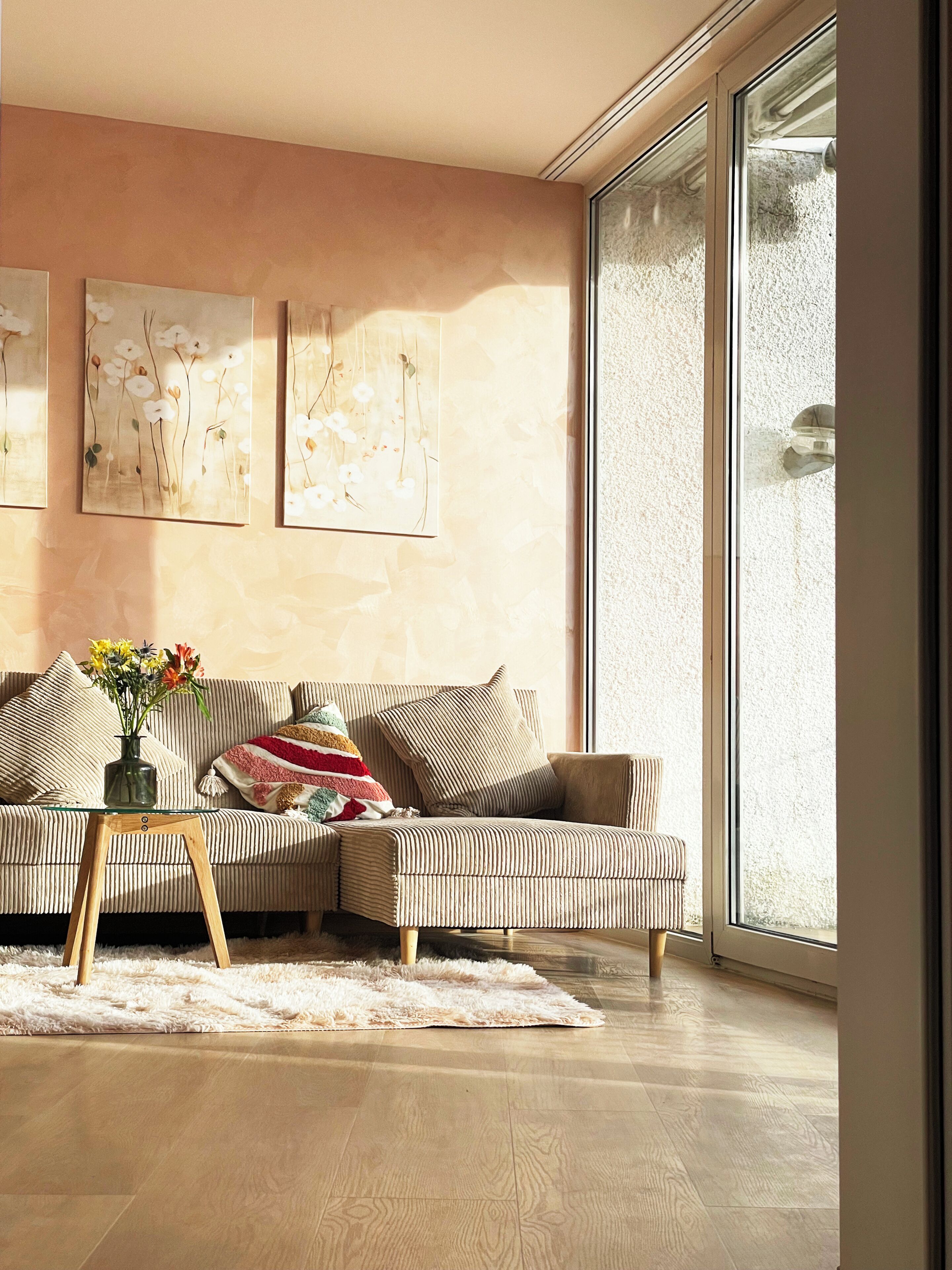 Ein modernes Wohnzimmer mit einem gestreiften Sofa, einem Glastisch und einem großen Fenster.