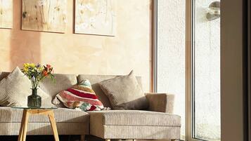 Ein modernes Wohnzimmer mit einem gestreiften Sofa, einem Glastisch und einem großen Fenster.