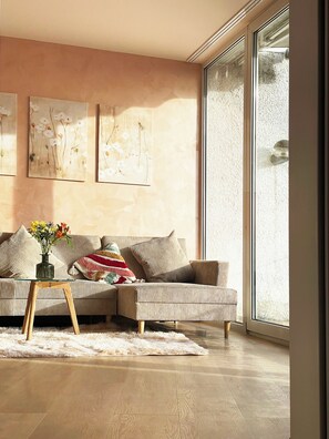 A modern living room with a striped sofa, a glass coffee table, and a large window. - Beautiful apartment Traumblick with balcony Bad Ems (Bad Ems)