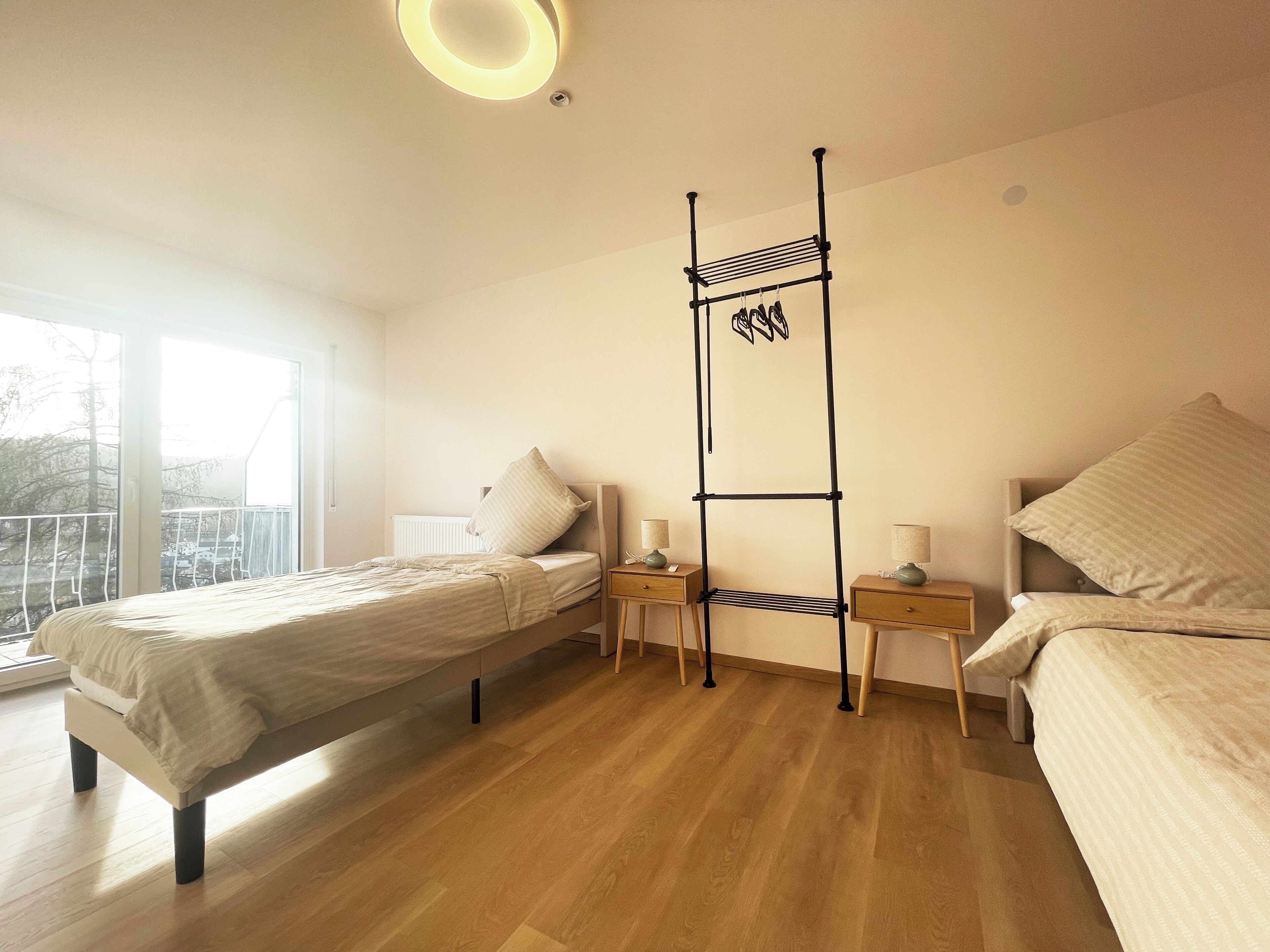 Ein Schlafzimmer mit einem Bett, zwei Nachttischen, einem Kleiderhaken und einem Fenster mit Blick.