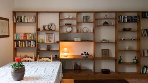 A room with a bed, a table with a vase, and a bookshelf filled with books and decorative items. - Near Beach - Pets - Bbq - Fireplace - Sleeps 10 (Leven)