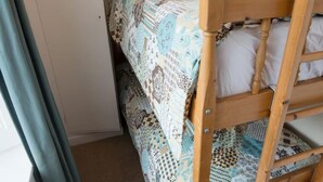 A bunk bed with a patterned bedspread, a wooden headboard, and a carpeted floor. - Near Beach - Pets - Bbq - Fireplace - Sleeps 10 (Leven)