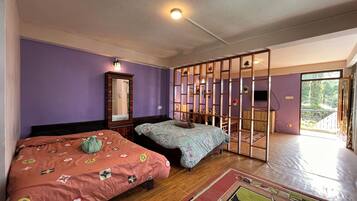 A bedroom with two beds, a wardrobe, a mirror, a partition, and a view of the outdoors.