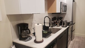 Eine moderne Küche mit Kaffeemaschine, Papierhandtuchhalter, Toaster und Mikrowelle.