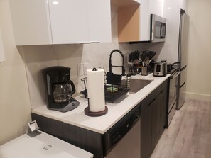 A modern kitchen with a coffee maker, paper towel holder, toaster, and a microwave. - Welcome To East Dallas! King Bed! Near It All (Dallas)