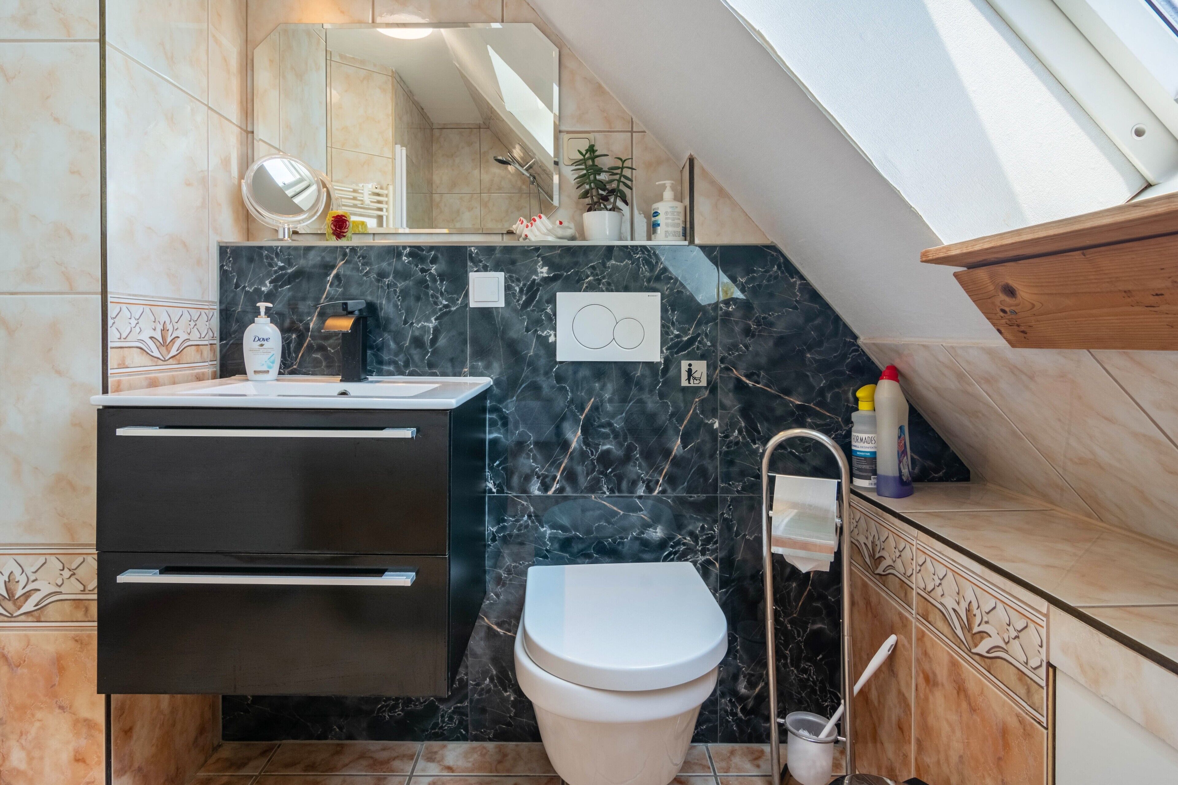 Une salle de bain avec des toilettes, un lavabo et un miroir.
