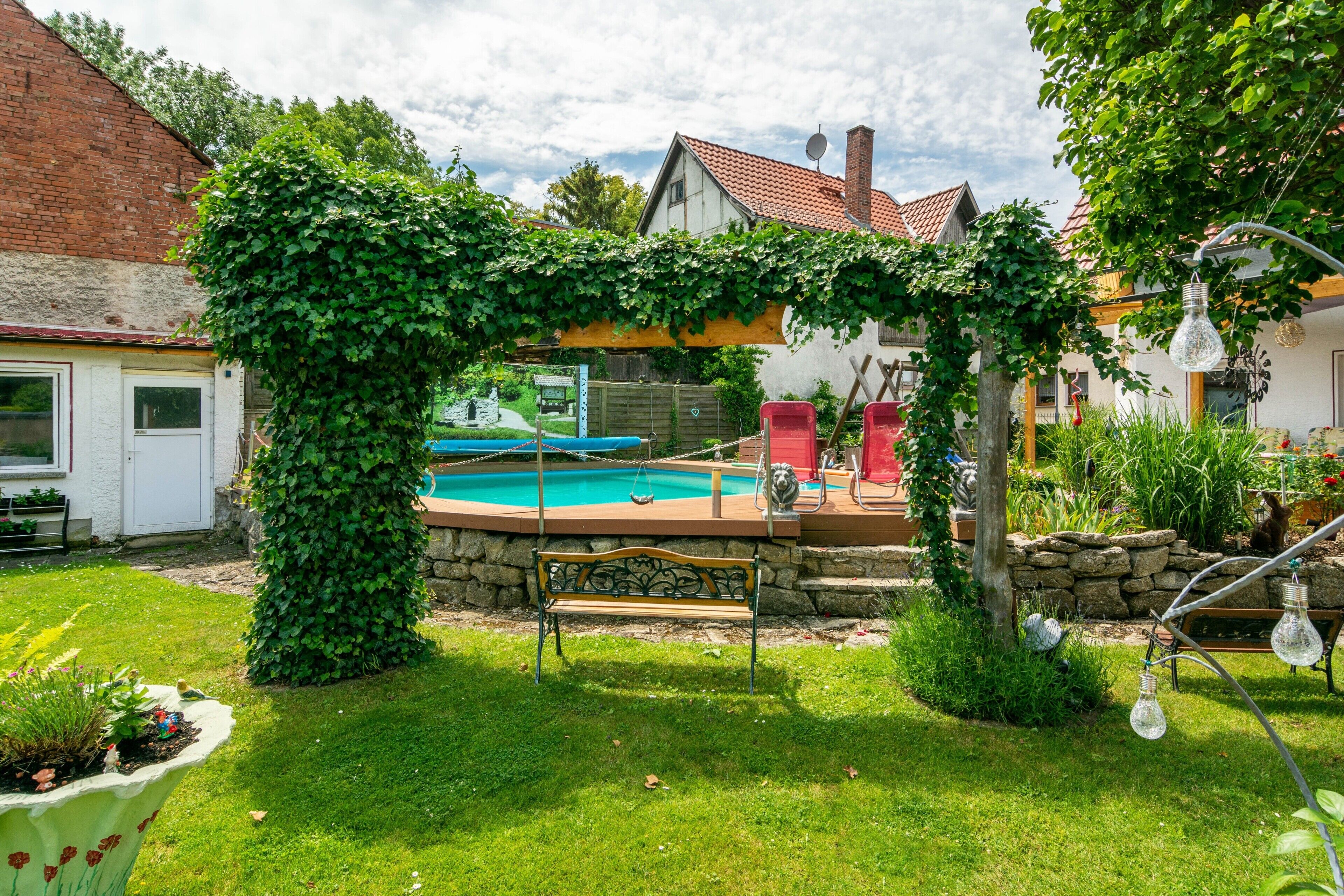 Un jardin avec une piscine, un banc et un mur en pierre.