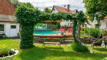 Un jardin avec une piscine, un banc et un mur en pierre.