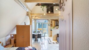 Une chambre à coucher comprenant un lit, une armoire en bois et un coin repas avec des chaises et une table.