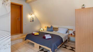 A bedroom with a bed, bedside table, lamp, and a view of the outside.