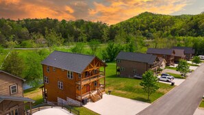 A multi-story wooden cabin with a balcony, surrounded by a residential area with houses and a road. - Creekside Paradise: Hot Tub,Arcade Games,NEAR PF! (Pigeon Forge)