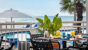 A balcony with a table set for breakfast, overlooking a pool and the ocean. - Seafront Double | The Shores | Oceanfront views, firepits | 2 Units (Daytona Beach)