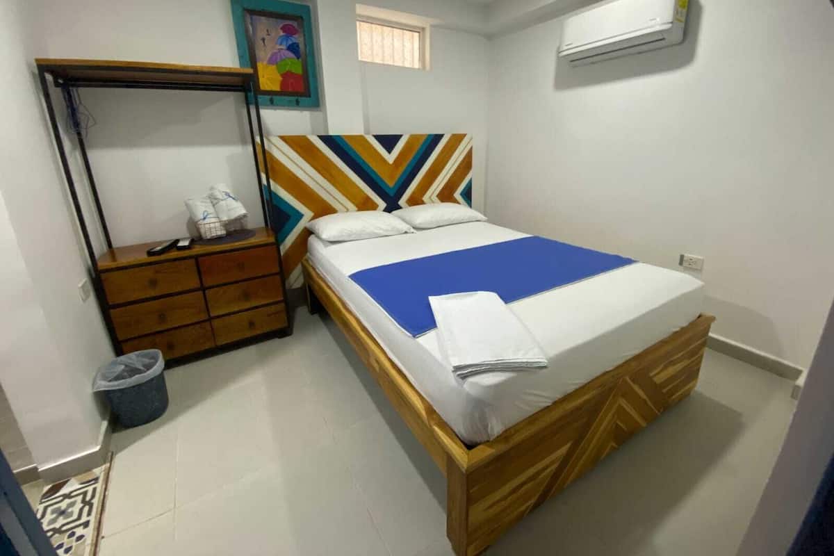 Une chambre à coucher comprenant un lit, une commode, un miroir et un appareil de climatisation.
