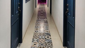 A hallway with patterned floor tiles, blue doors, and a ceiling light. - Nomadas hostels (Santa Marta)