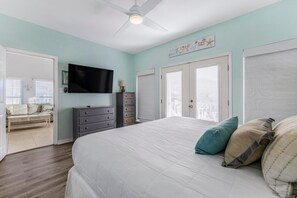 Ein Schlafzimmer mit einem Bett, einem Schminktisch, einem Fernseher und einem Deckenventilator.